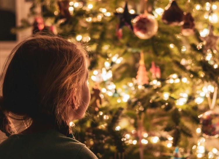 a close up of a person by a christmas tree