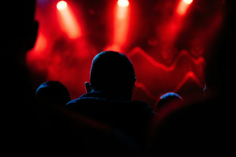 silhouettes of people at a concert with a bright red spotlight