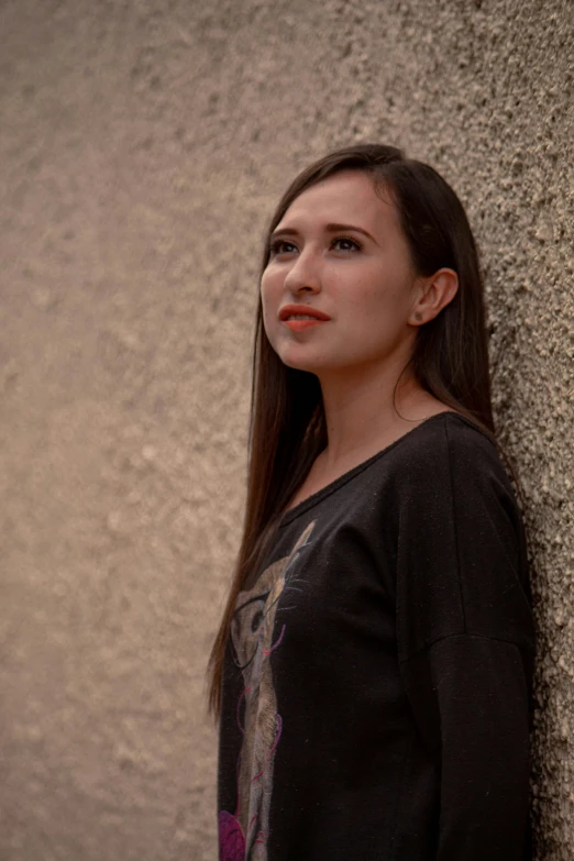 a girl is leaning against a wall with her hair hanging back and her eyes closed