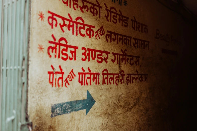 a foreign language on a wall with an arrow pointing towards the right