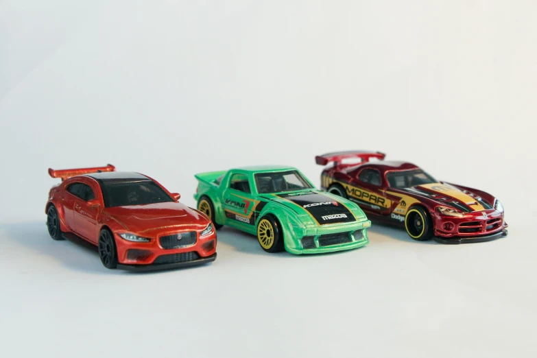 three colorful cars sit next to each other on a white surface