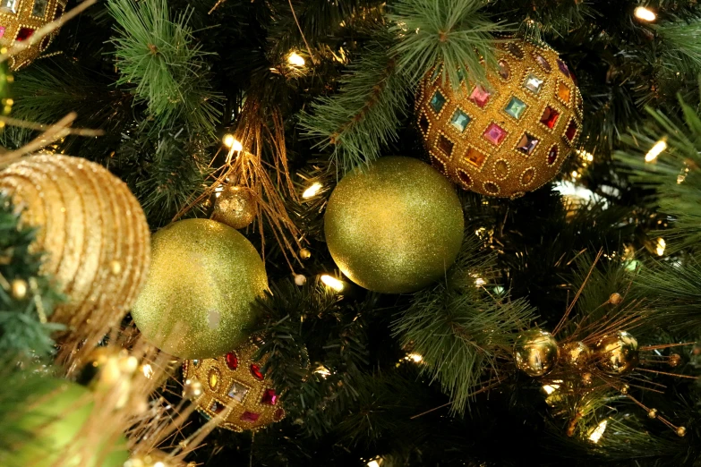 gold christmas decorations are arranged on the nches of a tree