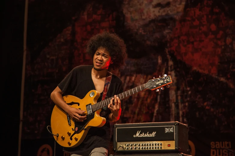 the guitarist is playing a yellow guitar in front of an amplifier