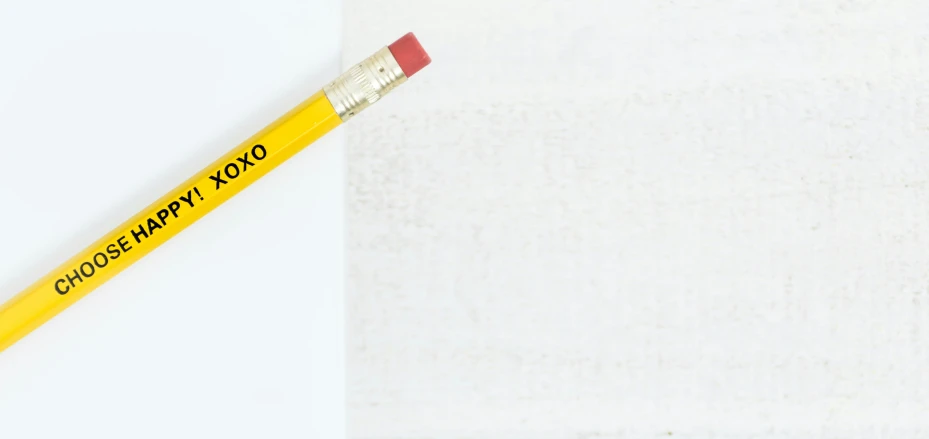 a yellow colored pencil resting on a white background