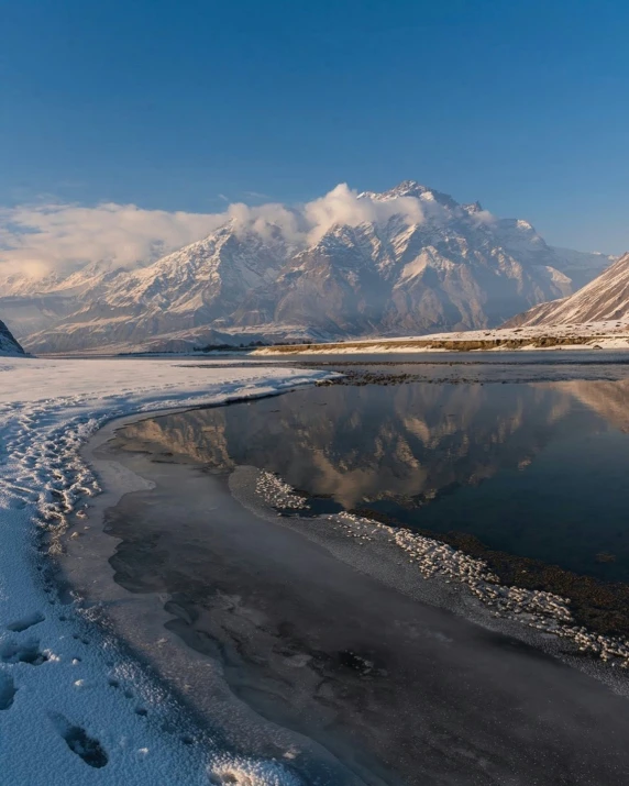 a person walking on a snowy field next to mountains