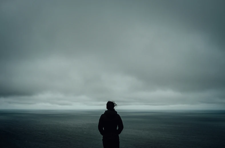 the dark man is standing on the beach with his kite