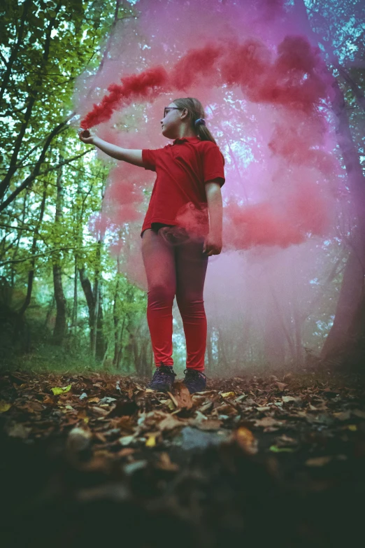 a young woman is posing with a colored stick in the woods