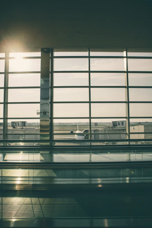 airport building with sun coming out of window and a large airplane in the distance