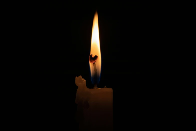 candle with a lit face in the darkness