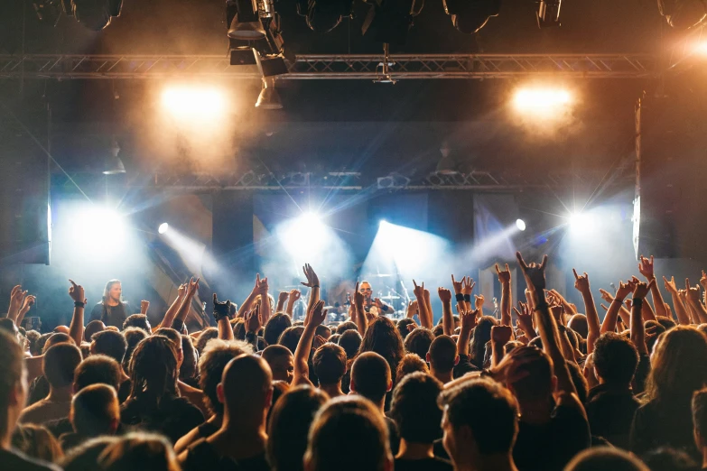an audience at a concert with their hands in the air