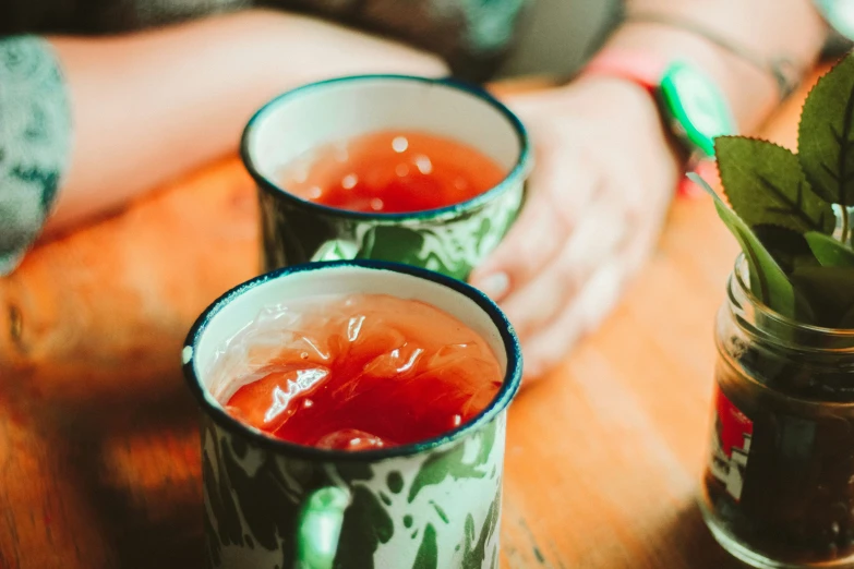 two glasses filled with drinks sitting on top of a wooden table