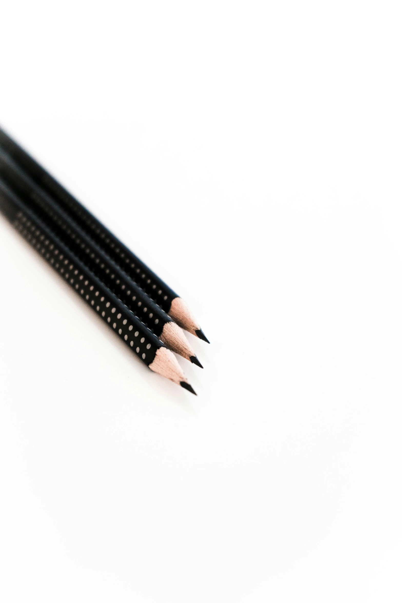 four black pencils lined up against the white surface