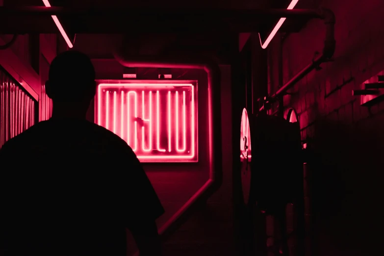 the man is standing in the corridor illuminated by red lights