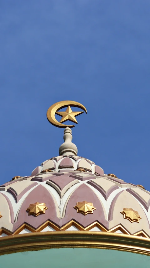 a star and crescent atop a dome against a blue sky