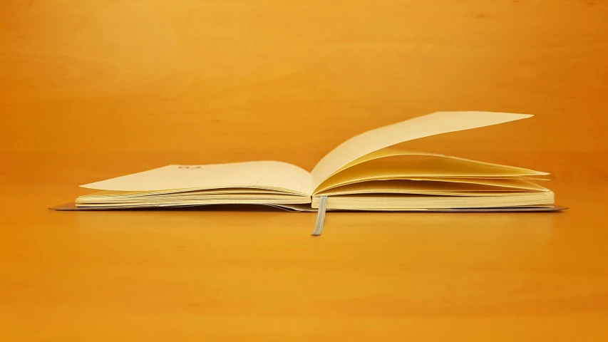 a folded open book sits on a yellow table