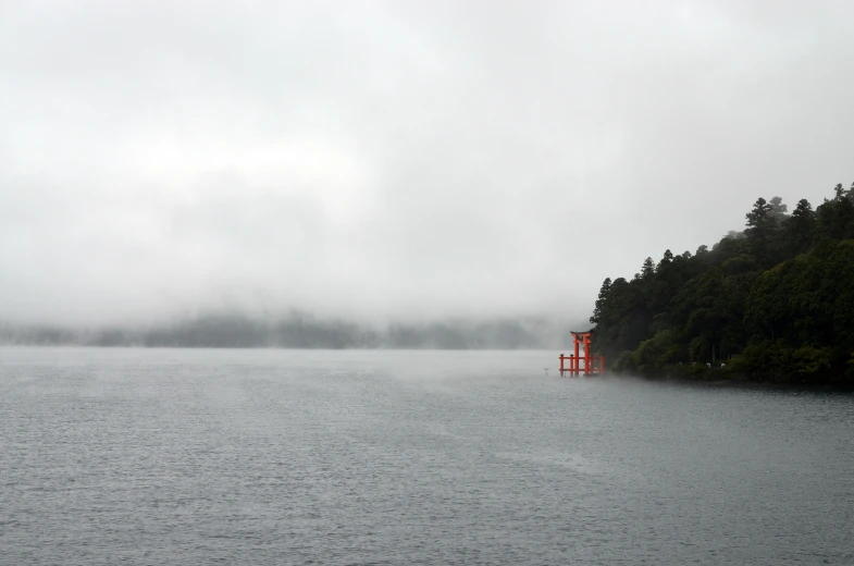 the foggy skies loom over the water with a house on it