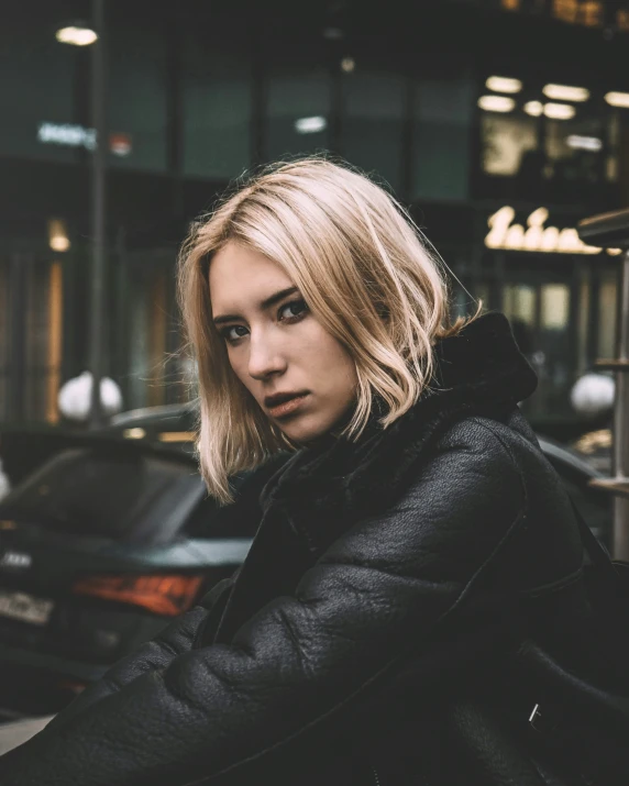 a blonde woman standing in front of cars