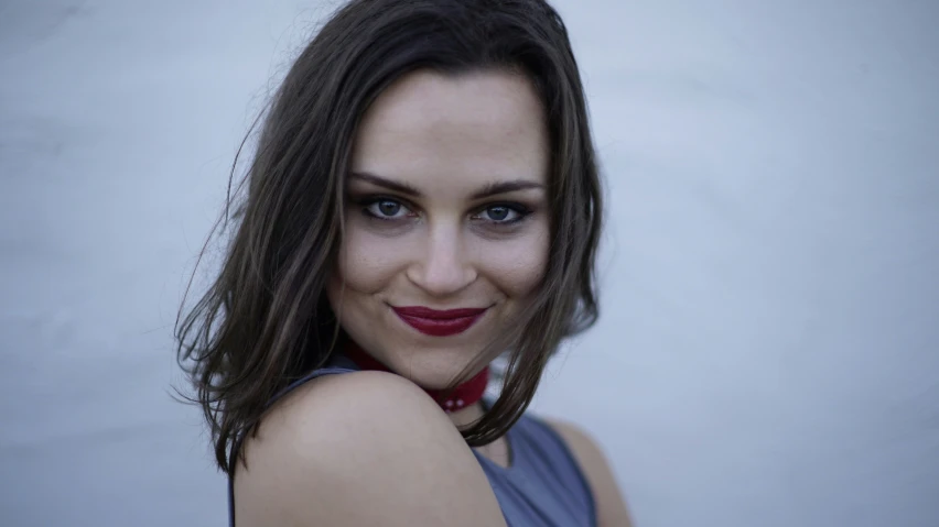 a woman with long dark hair and blue eyes wearing a red tie