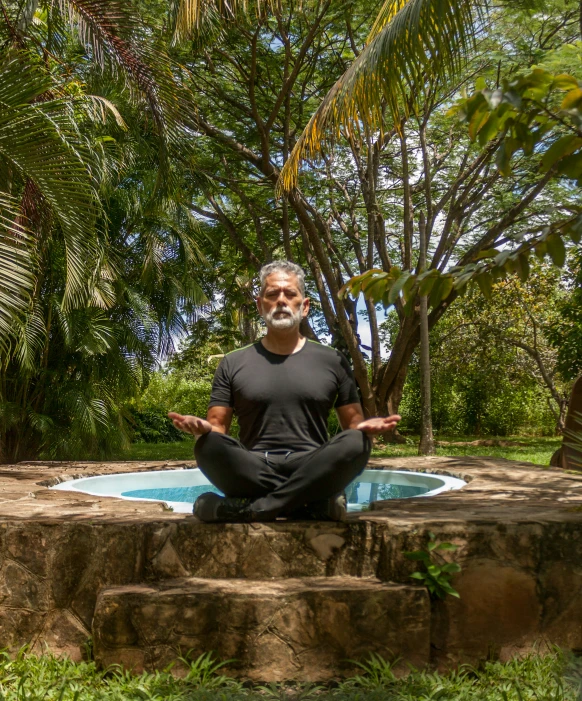 a man meditates in the garden with his hands up