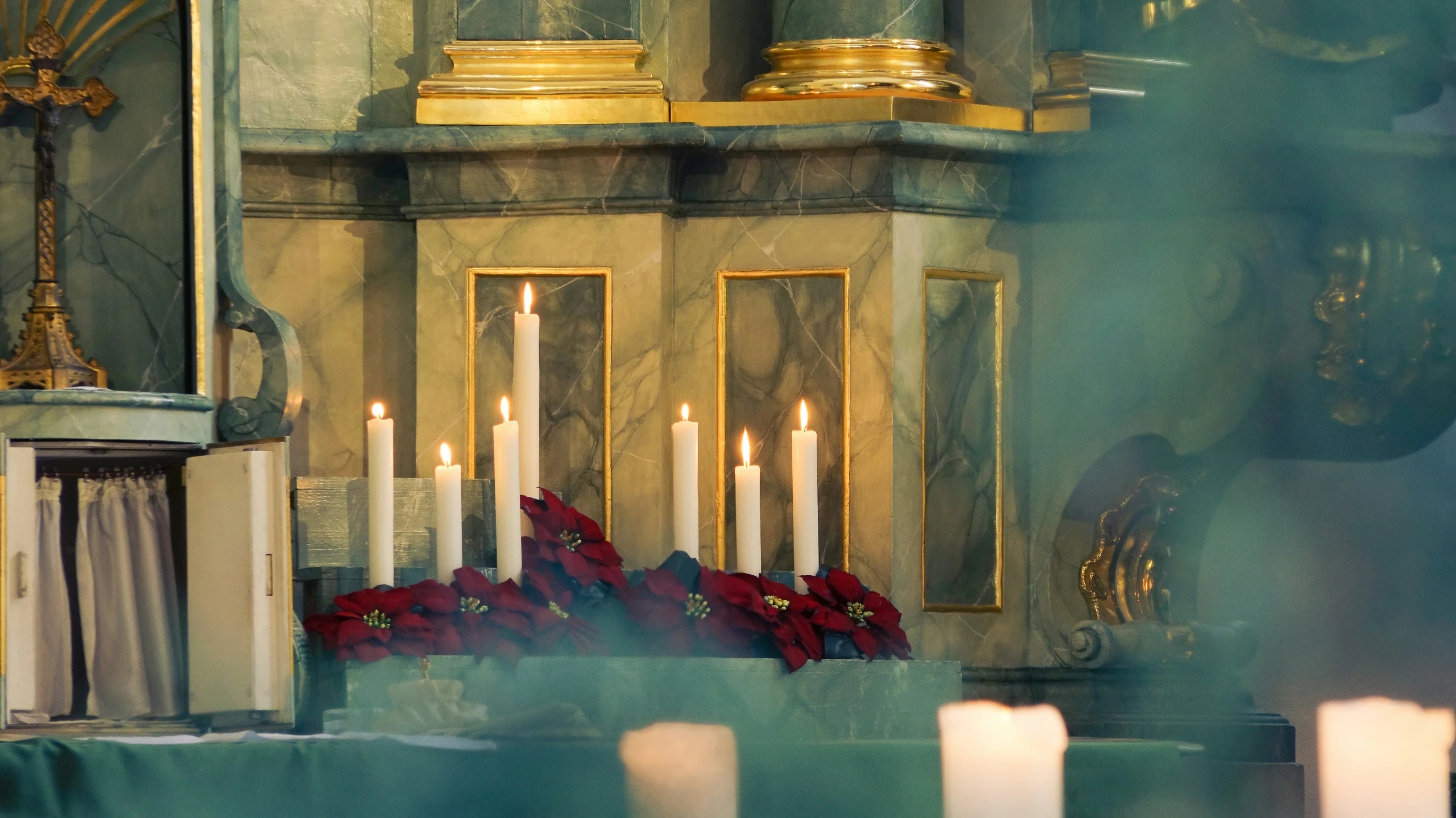 candles in a church with flowers and a clock