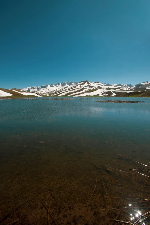 a snow covered mountain sits on the edge of a river