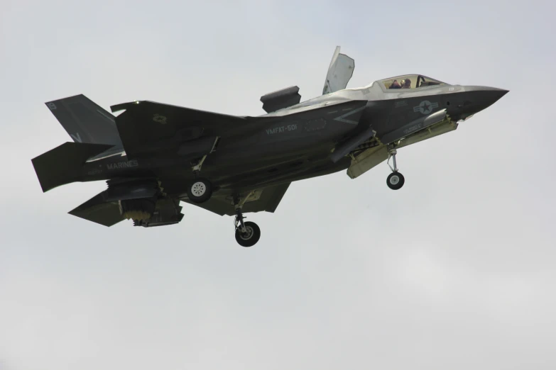 a fighter jet with landing wheels down is flying in the air