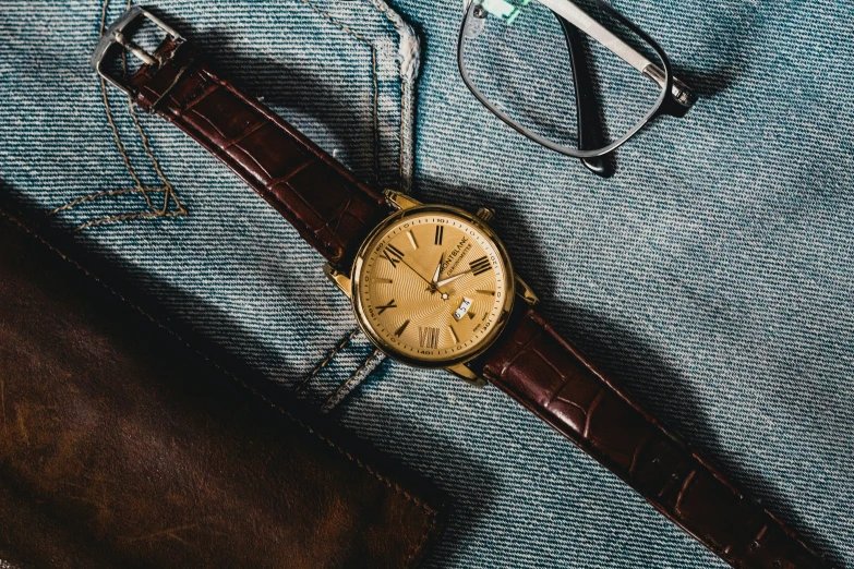 a gold watch and glasses laying on the table