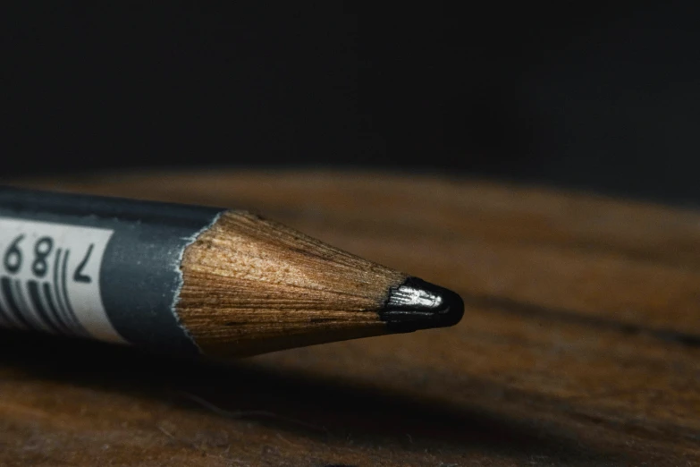 a close up of a pencil sitting on top of a wooden table