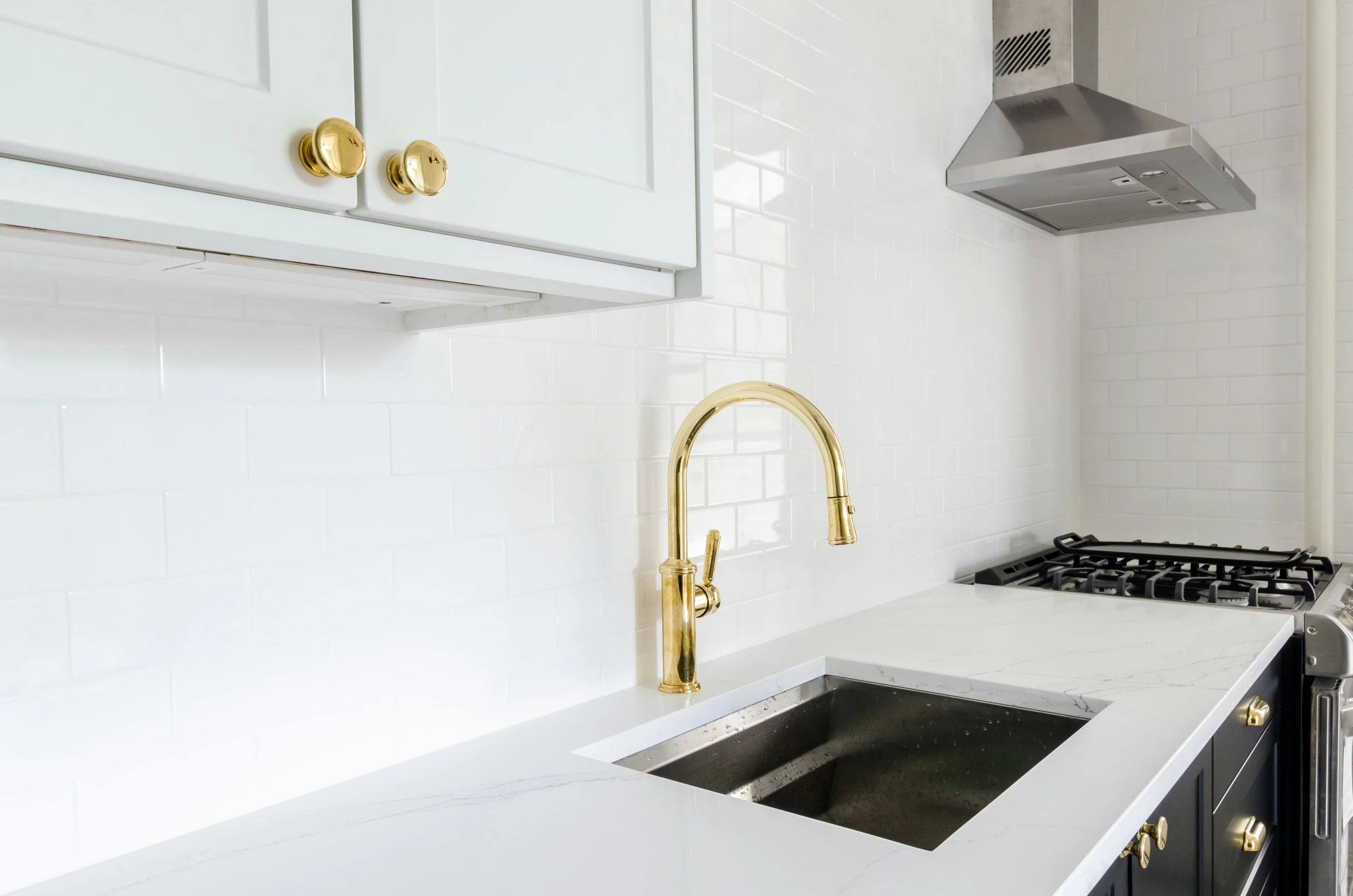 a kitchen with a sink, stove, and stove hood