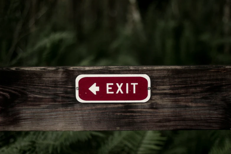 a red exit sign on a wooden post
