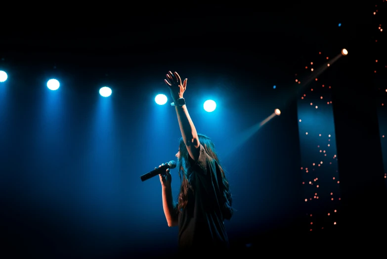 a woman is raising her arms up as she sings