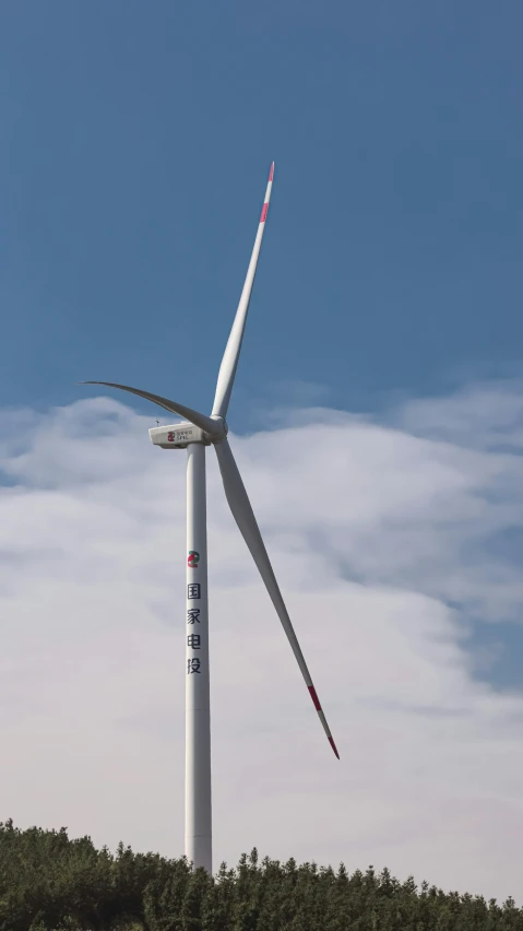 a large wind turbine next to a forest