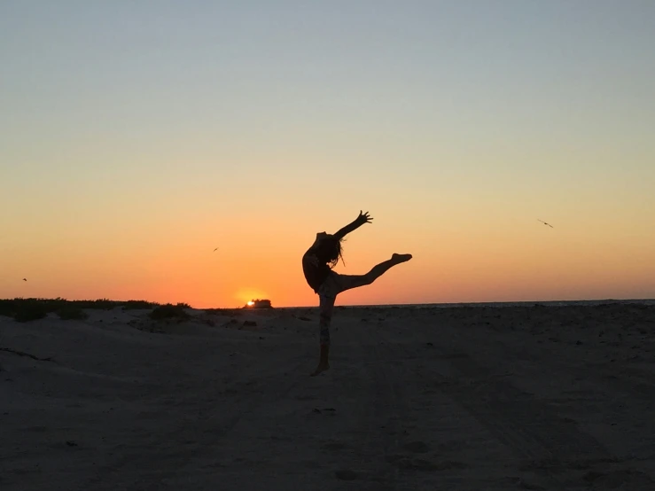 a woman doing a hand stand on the beach