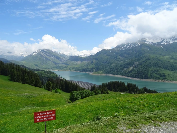 the mountain landscape shows a green meadow and lake