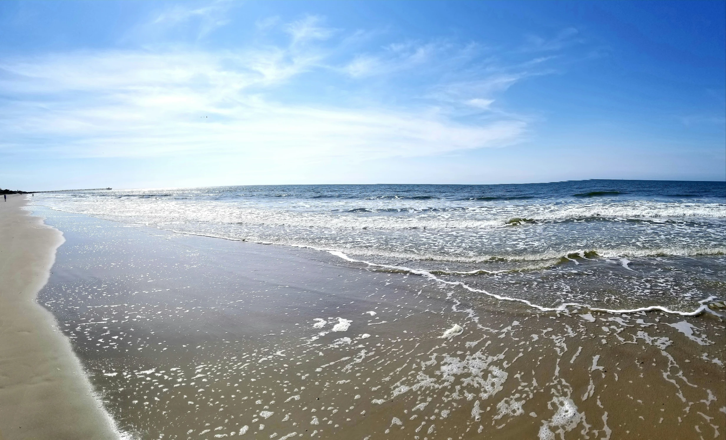 beach area with water coming in and sun shining