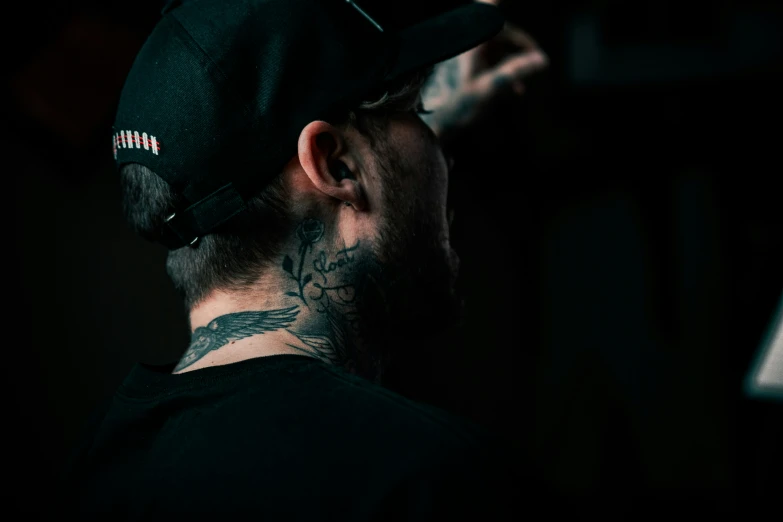 a man in a black hat with tattoos on his neck
