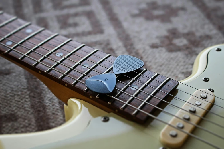 an electric guitar pick sits on top of the head of the frets