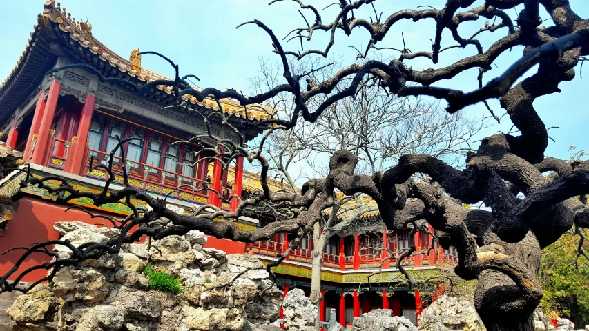 an oriental building sits next to rock formations