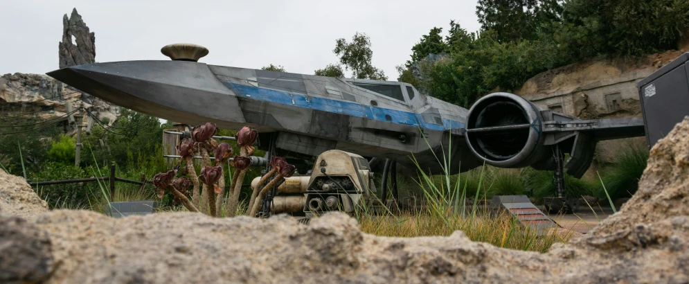 an old plane sits in the grass next to some rock formations