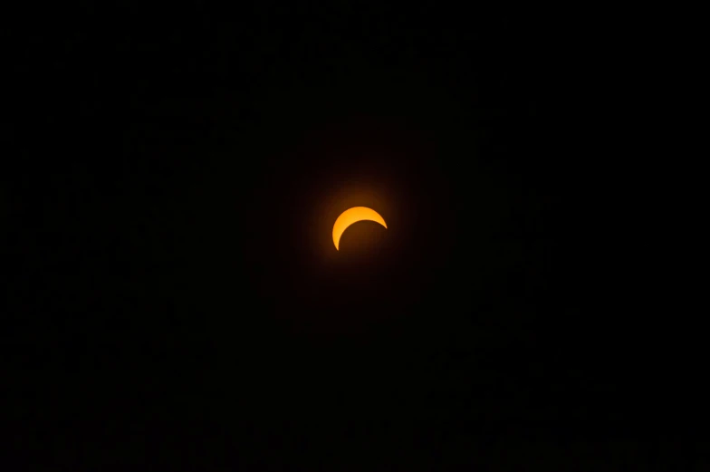 a bright, yellow and black eclipse can be seen through the dark night sky
