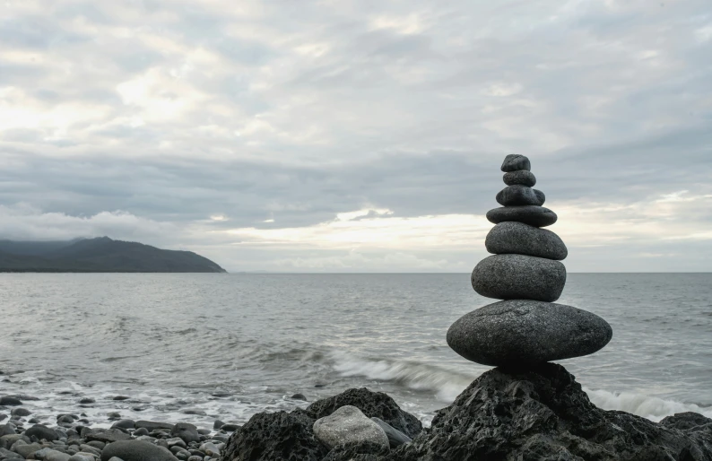 rocks stacked into piles on the shore by the water