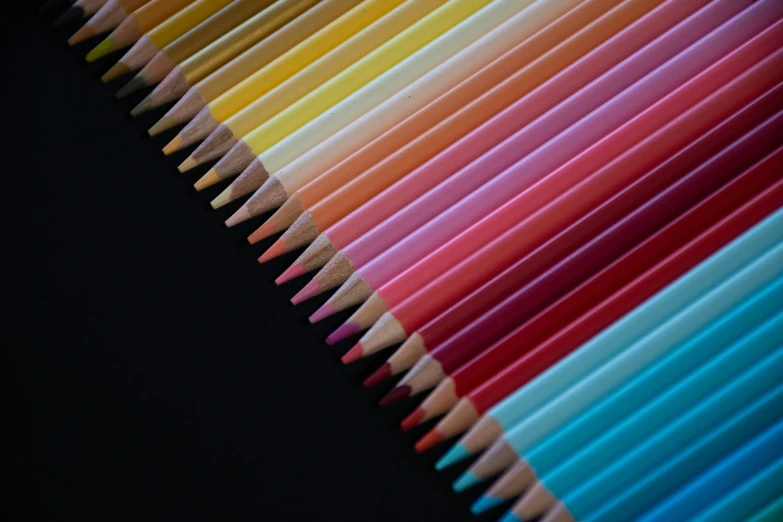 multi colored pencils sit in a row on a black background