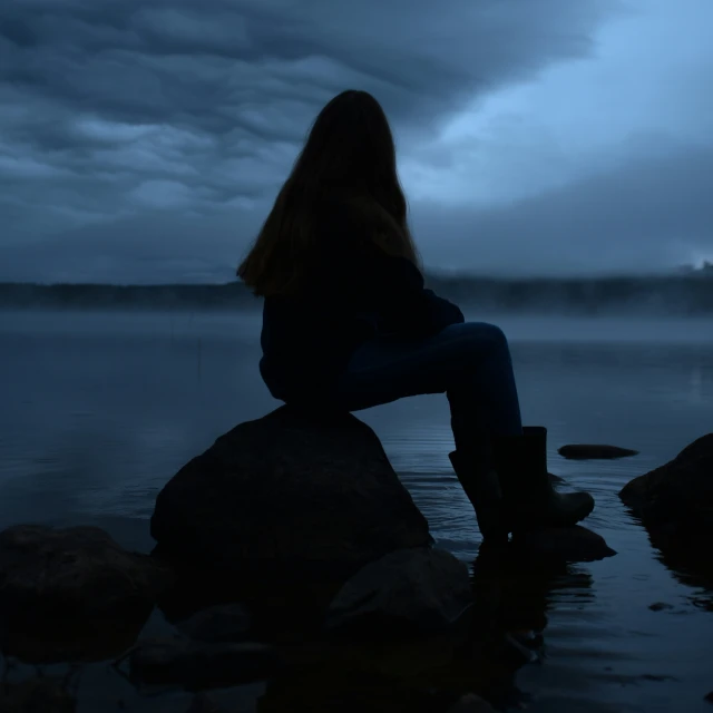 a woman sitting on rocks in the water