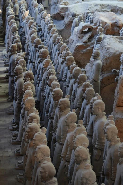 many statues are lined up along a stone wall