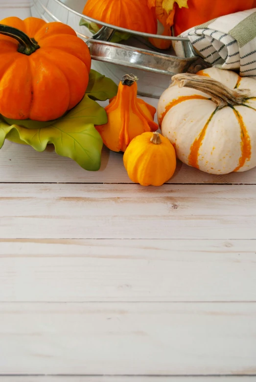 small pumpkins sit on a table next to decorative gourds