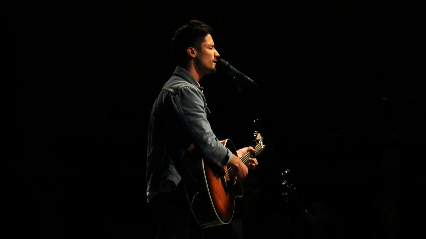 a man holding a guitar in front of a microphone