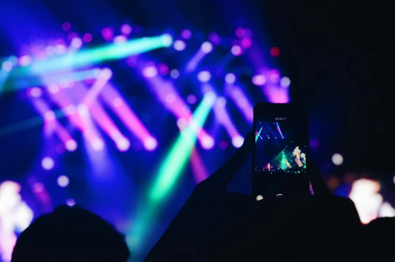 person taking pos on their cell phone with brightly lit show in the background