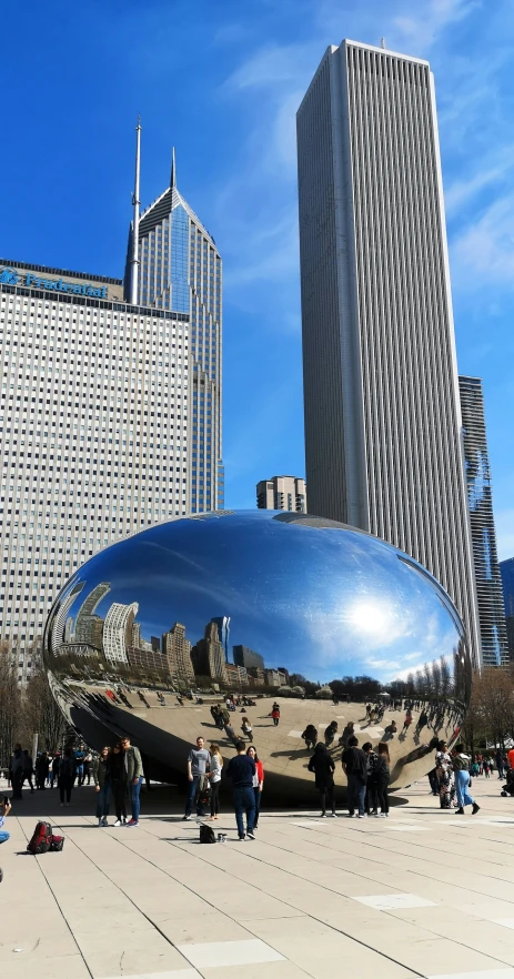 the big bean sculpture is on the ground in front of buildings