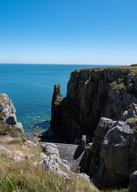 a man and woman looking at the ocean from a cliff