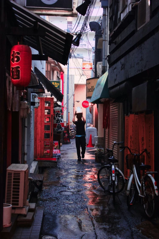 a narrow alleyway with bicycles parked on it and some people holding umbrellas